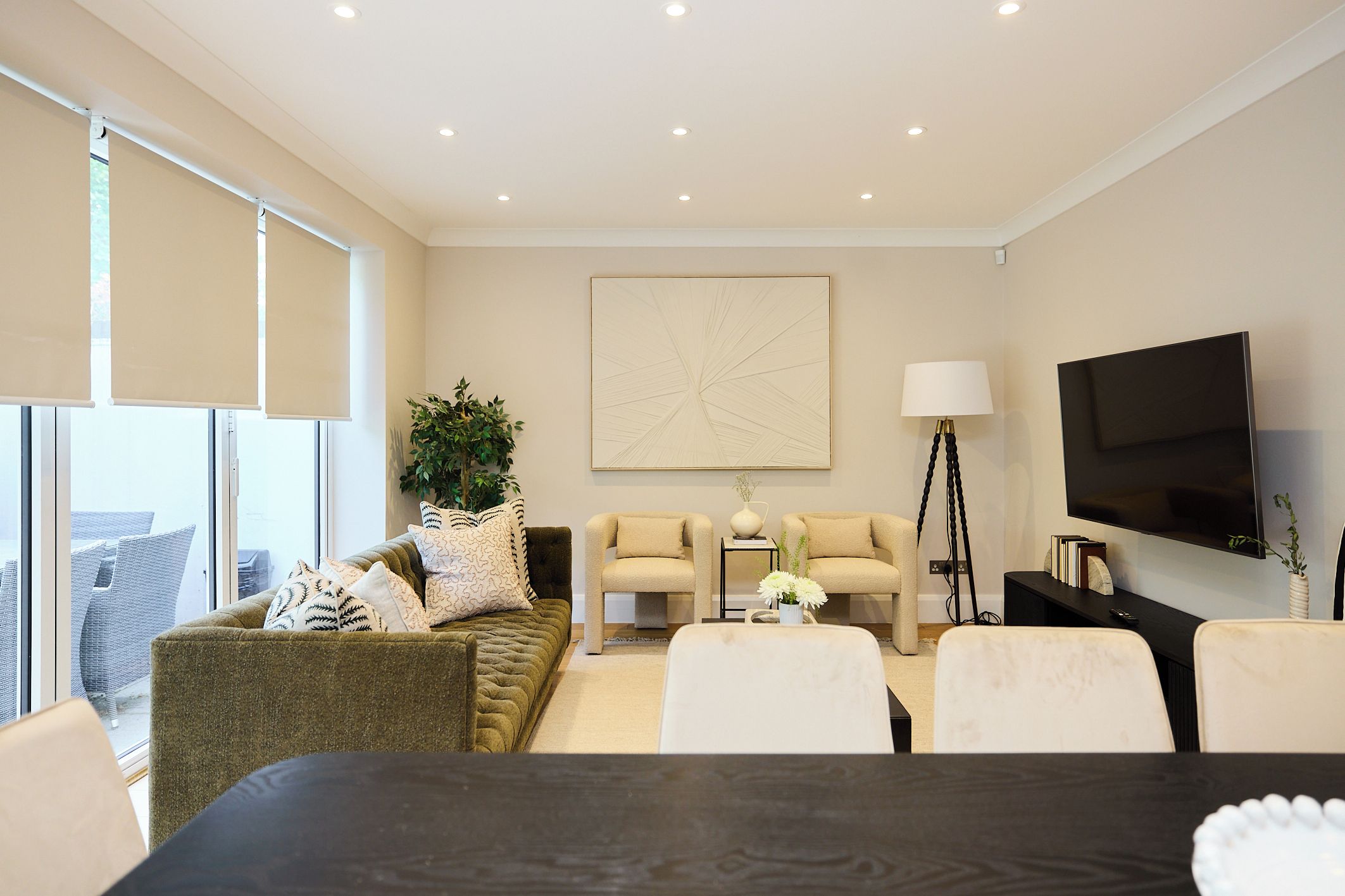 Una sala de estar moderna con un sofá, sillas, una mesa de centro, un televisor y un ventanal grande.