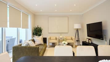 Una sala de estar moderna con un sofá, sillas, una mesa de centro, un televisor y un ventanal grande.