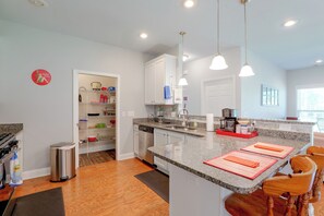 Eine moderne Küche mit Granit Arbeitsplatten, Edelstahlgeräten und Pendelleuchten.