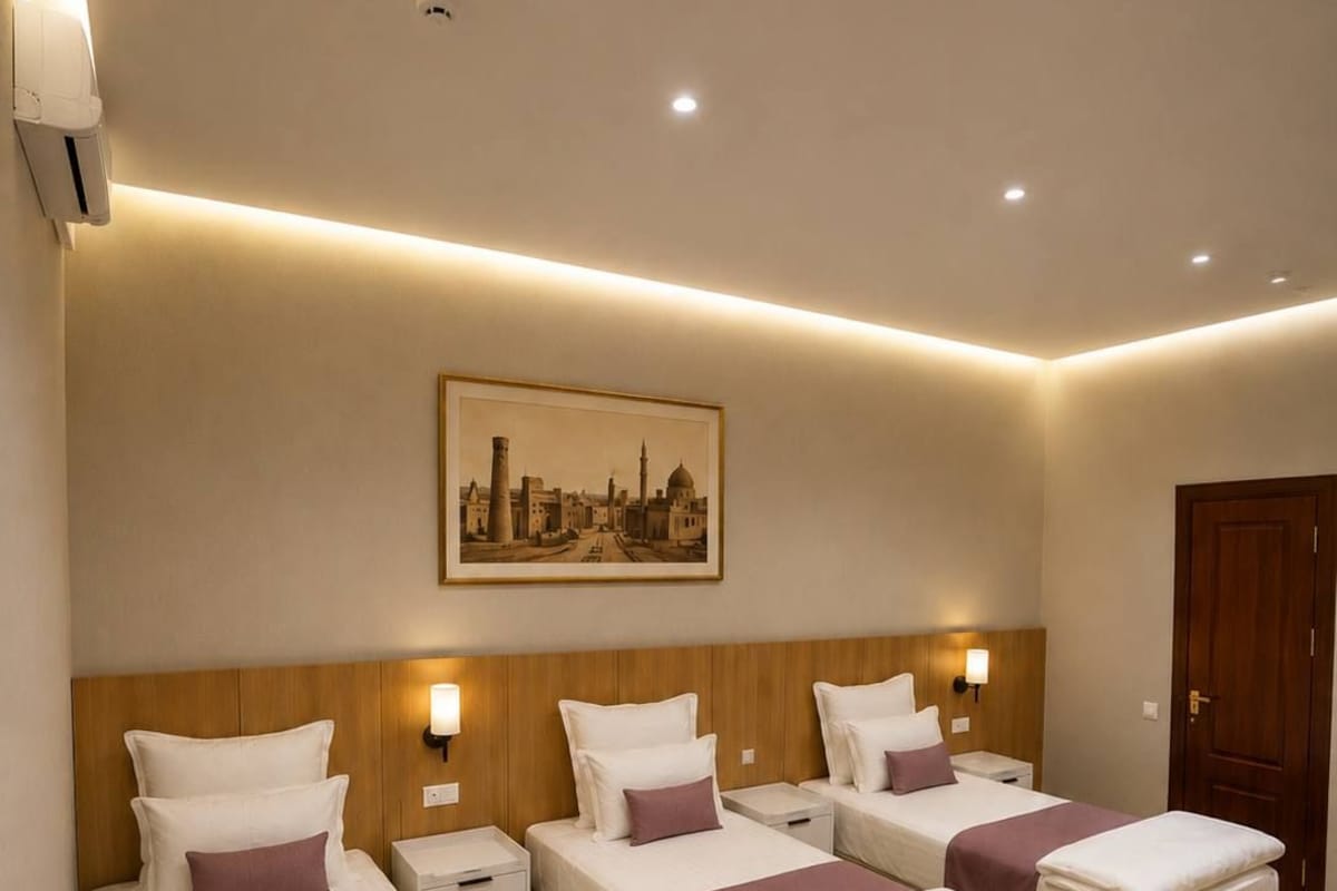 A hotel room with three beds, wooden headboards, a cityscape painting, and a wooden floor.