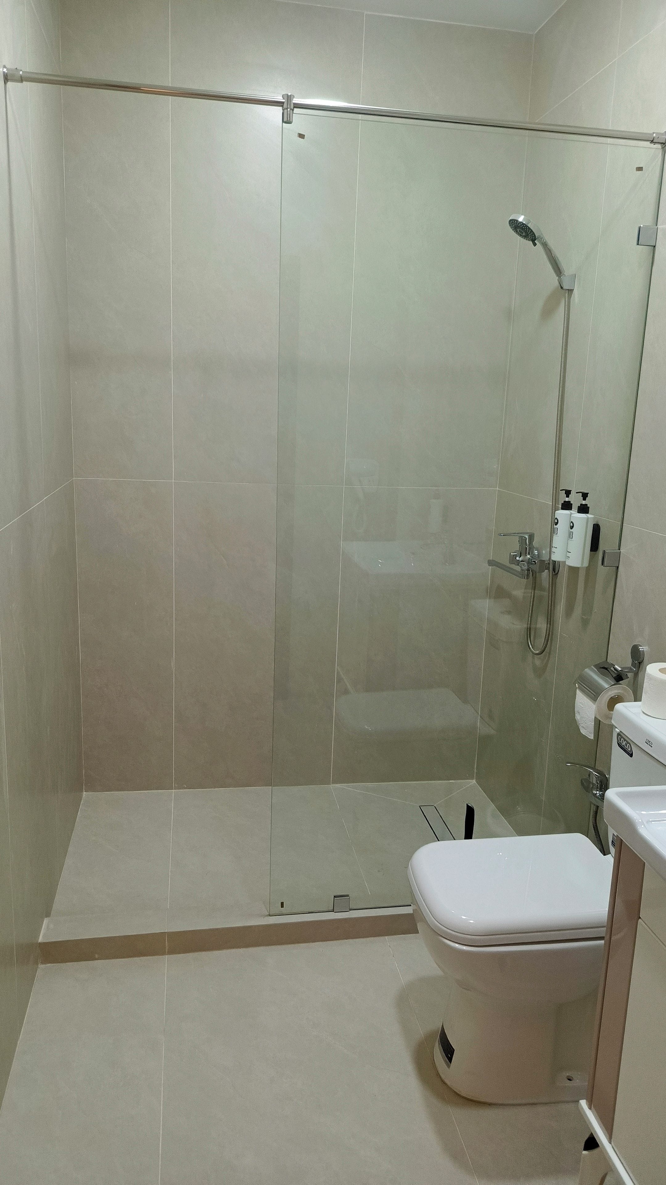 Un baño moderno con ducha envuelta en vidrio, inodoro y lavamanos.