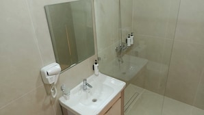 A bathroom with a white sink, a mirror, and a glass shower enclosure. - Darvaza Boutique Hotel (Bukhara)