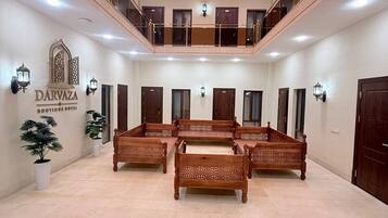 Un vestíbulo de hotel con una zona de estar central, varias puertas y un letrero que dice 'DARVAZA BOUTIQUE HOTEL'.
