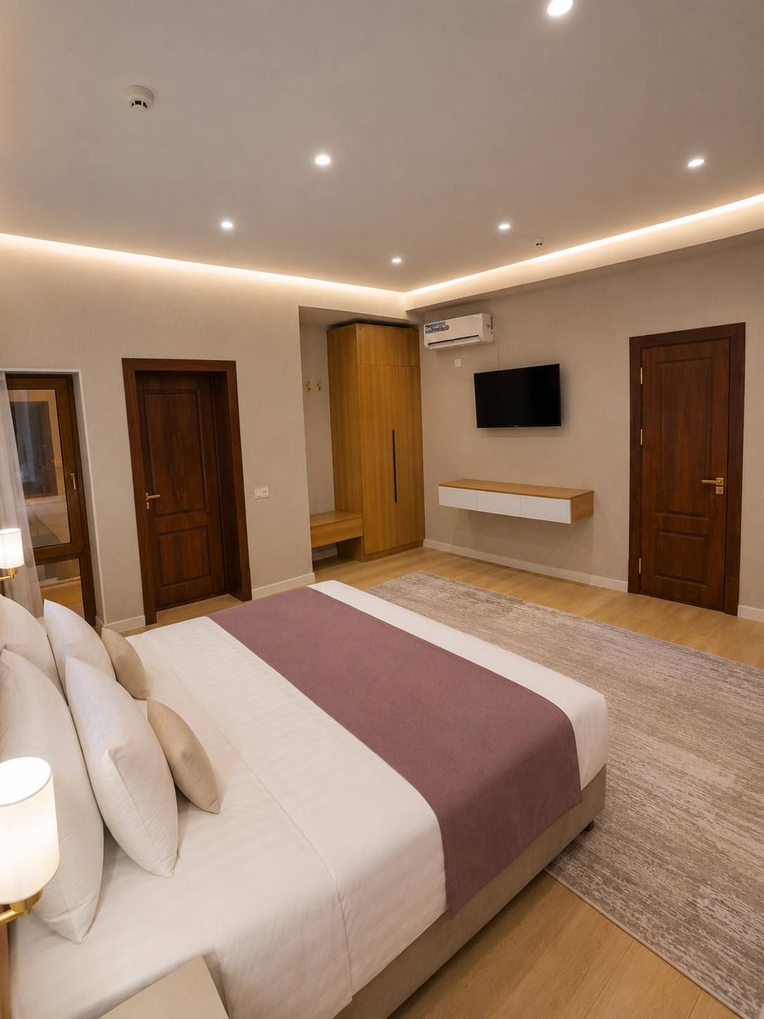 Une chambre à coucher avec un lit, un téléviseur fixé au mur et une armoire.