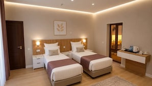 A modern hotel room with two beds, a desk, and a bathroom visible through a glass door. - Darvaza Boutique Hotel (Bukhara)
