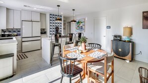 Eine moderne Küche mit weißen Schränken, einem Essbereich mit Holztisch und Stühlen sowie einer Kücheninsel.