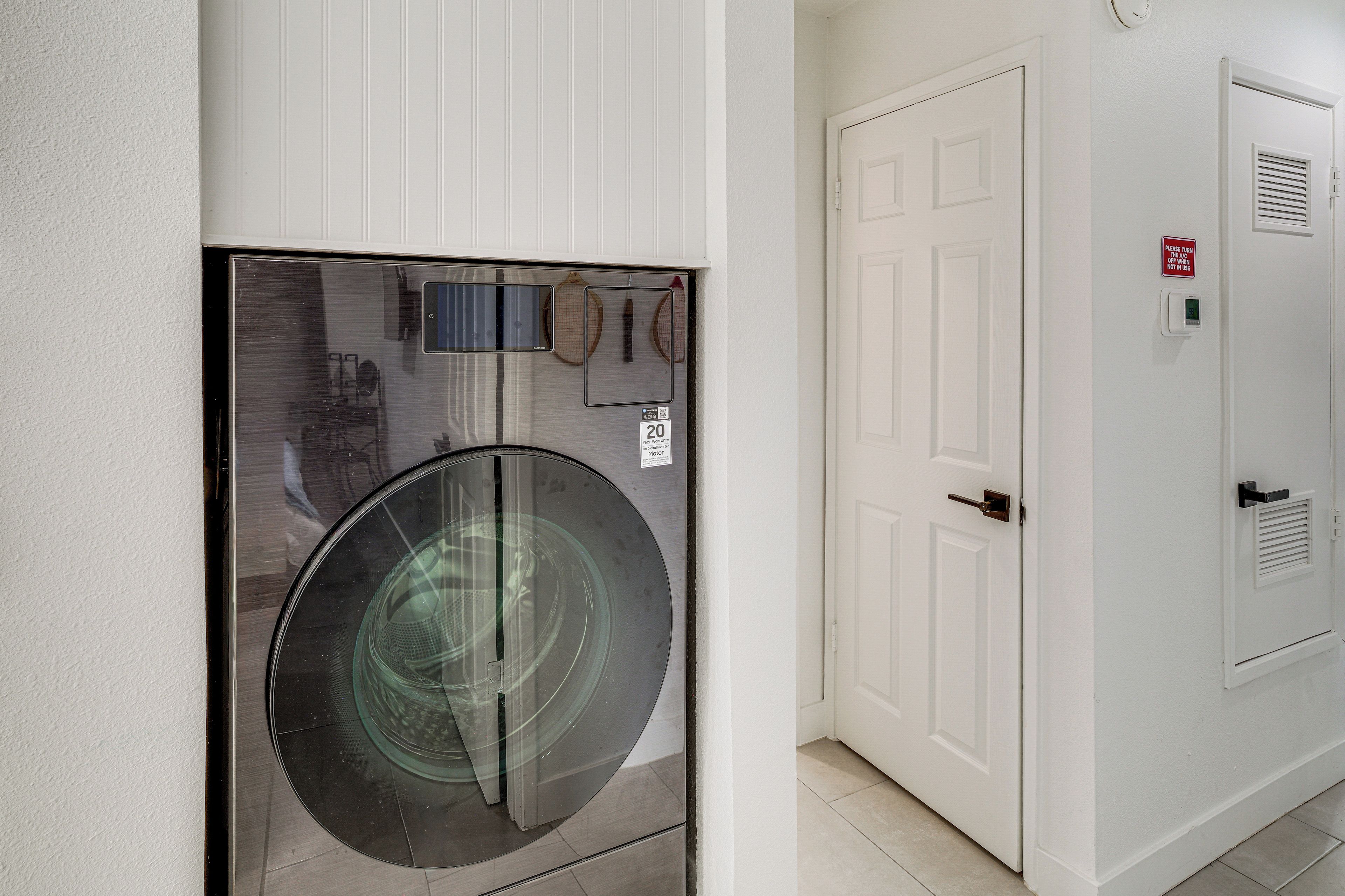 A wall-mounted washing machine with a control panel and a door with a sign indicating a 20-year warranty.