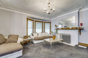 A living room with a sofa, a coffee table, a fireplace, and a chandelier.
