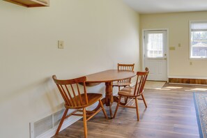 A dining area with a wooden table and chairs, a white door, and a window with blinds. - On-Site Ponds! Peaceful Franklin Studio (Franklin)