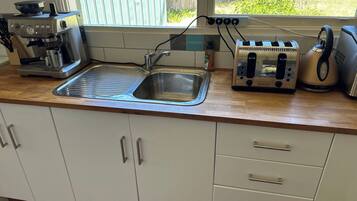 A kitchen with a sink, a coffee maker, a toaster, and a kettle.