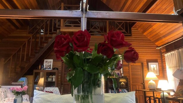 Ein Holzinterieur mit einem Tisch, auf dem eine transparente Vase mit roten Rosen steht.