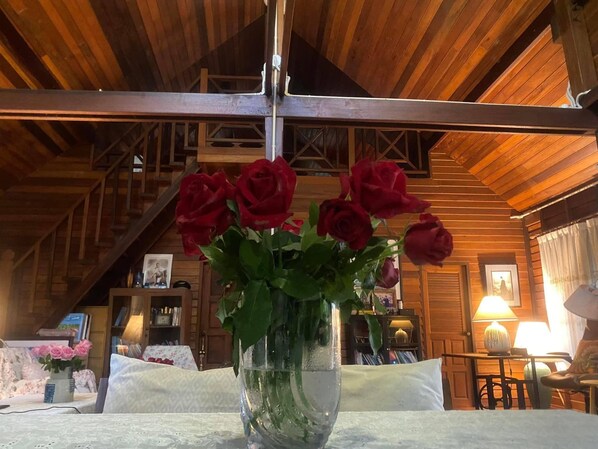 A wooden interior with a table holding a clear vase with red roses. - the NOW by Kru Se Mini Villa (Chiang Mai)