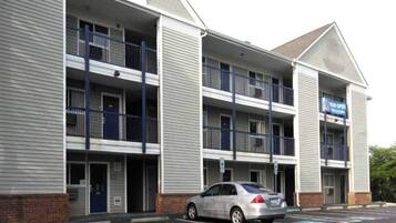A multi-story hotel with a parking lot and a car parked in front.