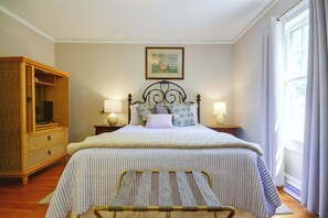 A neatly arranged bedroom with a bed, bedside lamps, a wicker wardrobe, and a framed picture on the wall. - Wine Country Retreat! Sun Porch, Private Yard (Lexington)