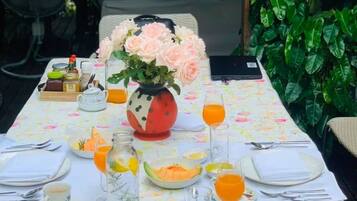 Ett bord dukat för en måltid med olika rätter, en vas med blommor och en bärbar dator.