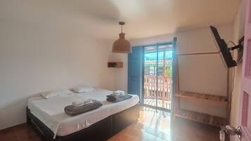 A bedroom with a bed, a hanging light fixture, a sliding door to a balcony, and a door with a key lock.