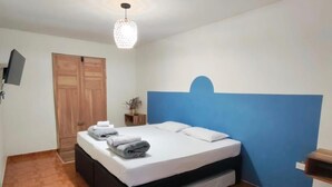 Un dormitori amb un llit, un armari, una televisió i un llum decoratiu.