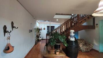 A spacious interior with a wooden staircase, potted plants, and a hanging light fixture.