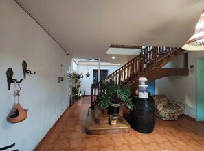 A spacious interior with a wooden staircase, potted plants, and a hanging light fixture.
