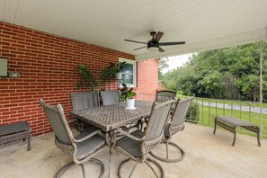 Eine überdachte Terrasse mit Backsteinmauer, einem Tisch mit Stühlen und einem Deckenventilator.