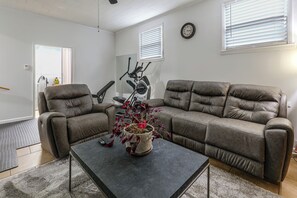 Un salon avec deux canapés, une table basse et une horloge murale.