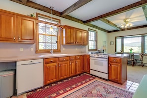 A kitchen with wooden cabinets, a dishwasher, a stove, and a large window. - Ride, Ski & Explore: Franklin, Vermont Getaway (Franklin)