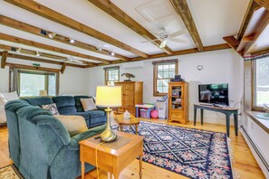 A living room with a sofa, a lamp, a television, and a ceiling fan. - Ride, Ski & Explore: Franklin, Vermont Getaway (Franklin)
