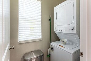 A laundry room with a front-loading washing machine, a dryer, and a trash bin. - Family Getaway, 5 Mi to Silver Dollar City (Branson)