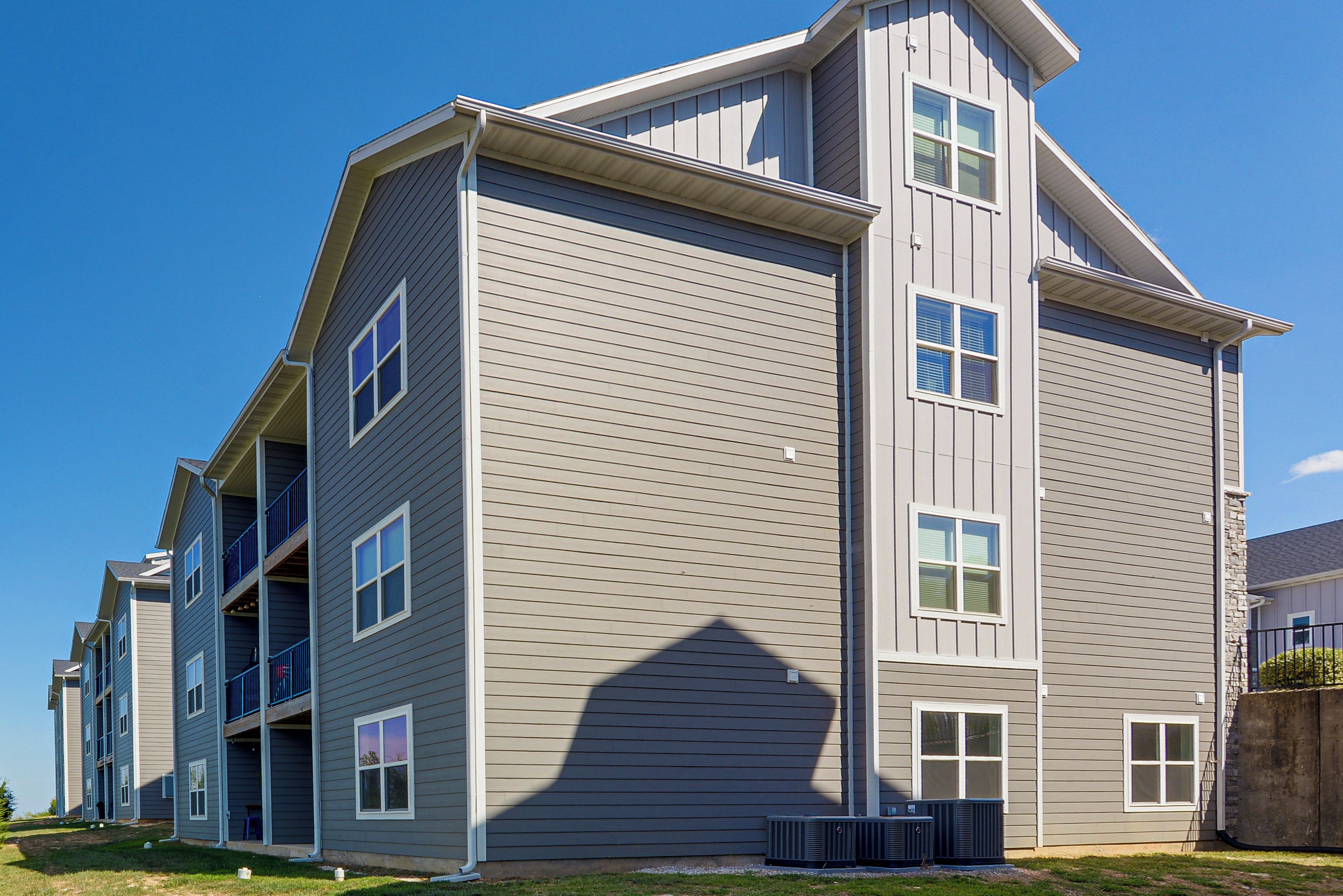A multi-story residential building with a modern design, featuring a flat roof and large windows.