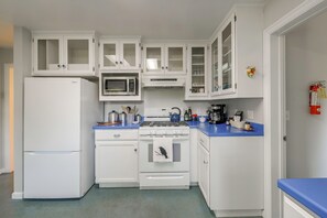Eine Küche mit weißen Schränken, einem Kühlschrank, einer Mikrowelle, einem Herd und einem Spülbecken.