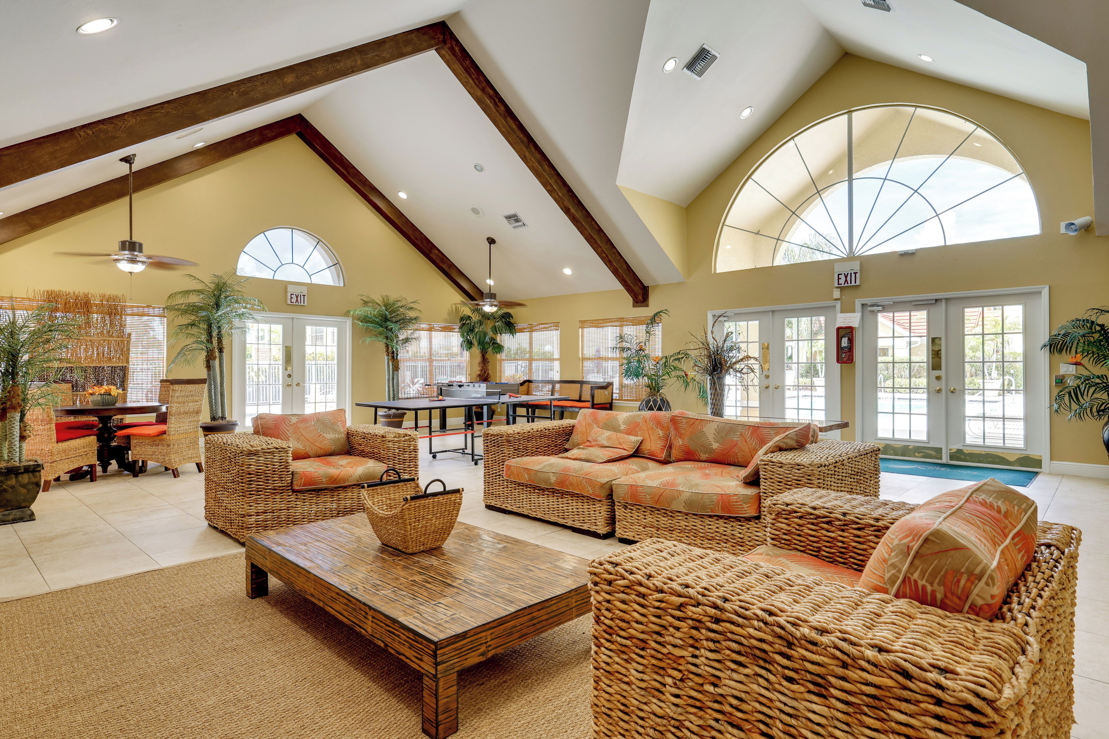 A spacious indoor area with high ceilings, wicker furniture, and large windows allowing natural light.