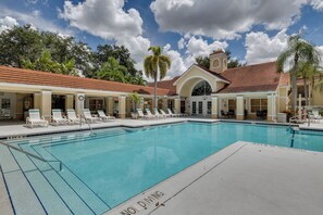 A pool area with lounge chairs and a building with a red-tiled roof. - Venetian Palms Condo: Pool, Hot Tub & Tennis! (Fort Myers)
