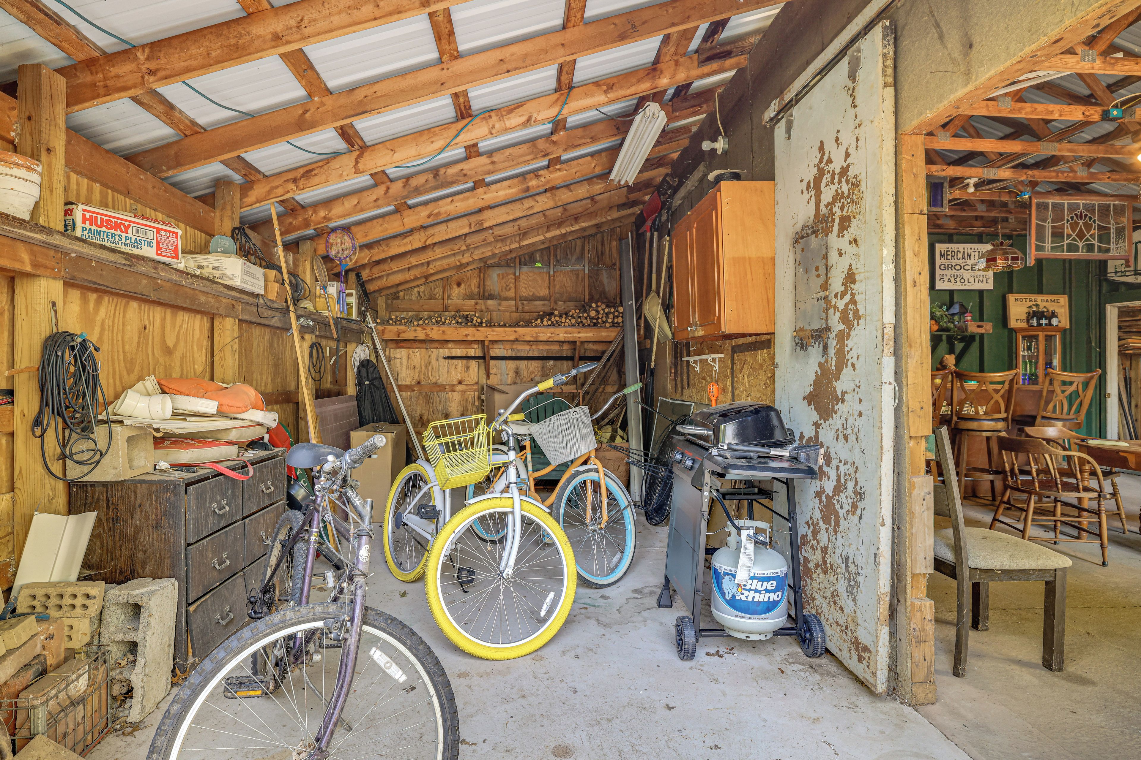 Interior rústic d'un graner, amb bigues de fusta, bicicletes i diverses eines.