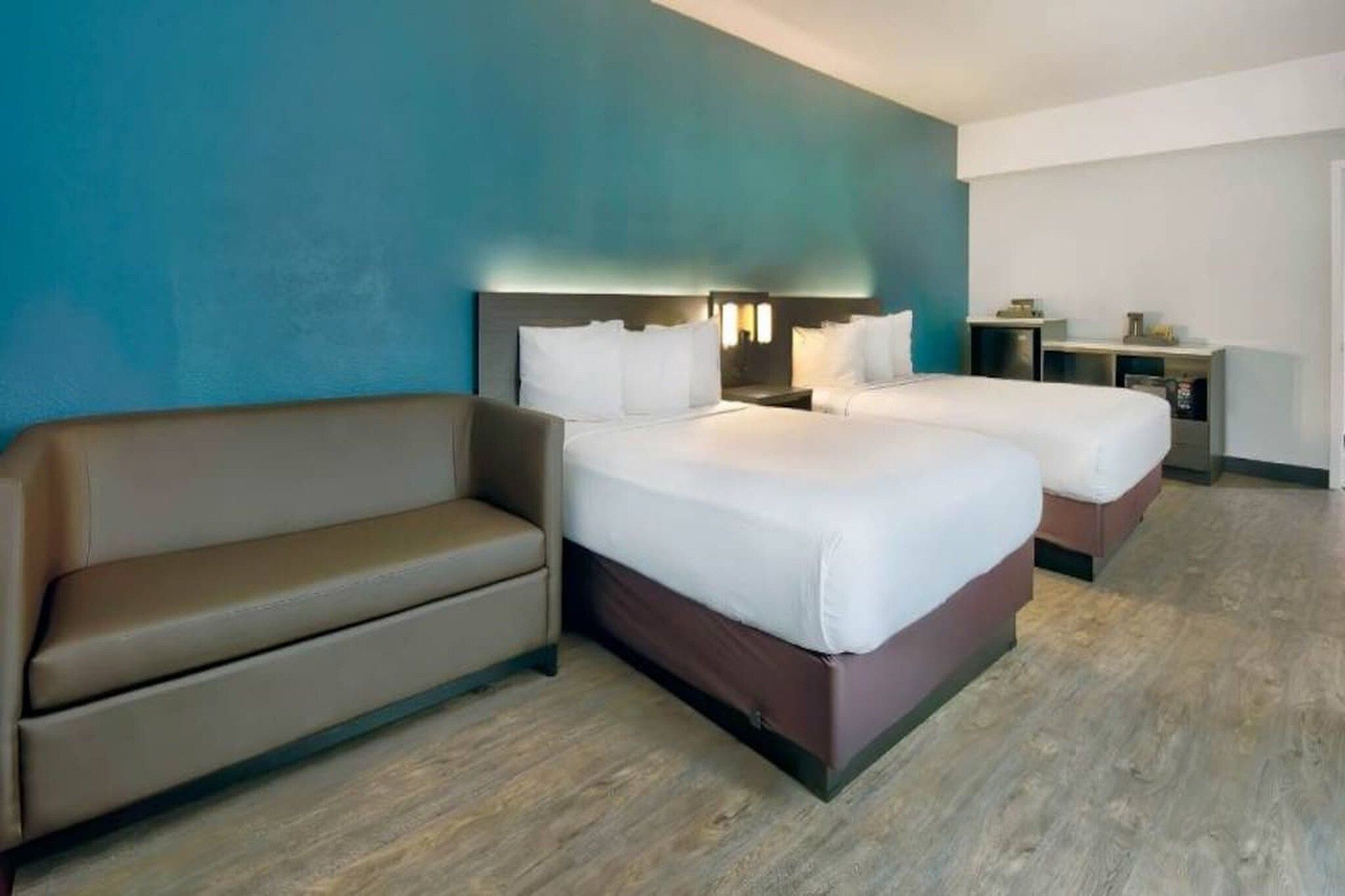 Ein Hotelzimmer mit zwei Betten, einem Sofa, einem Schreibtisch und einem Nachttisch.