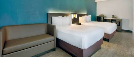 A hotel room with two beds, a sofa, a desk, and a nightstand.
