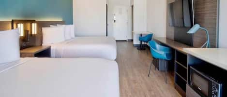A hotel room with two beds, a desk, a chair, a TV, and a microwave.