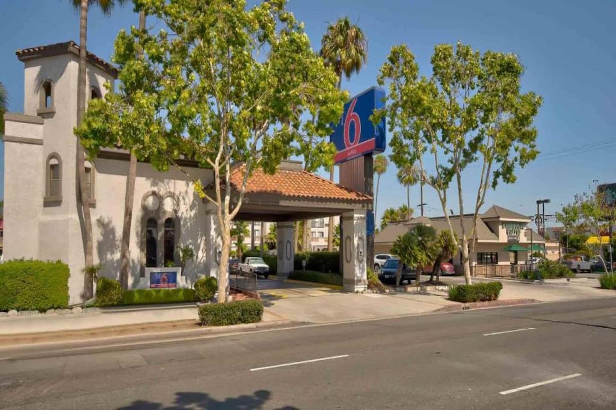 A hotel with a prominent '6' sign, a covered entrance, and a parking lot.