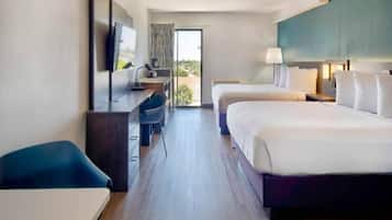 Une chambre d’hôtel avec deux lits, un bureau, une chaise, une télévision et une vue sur l’extérieur.