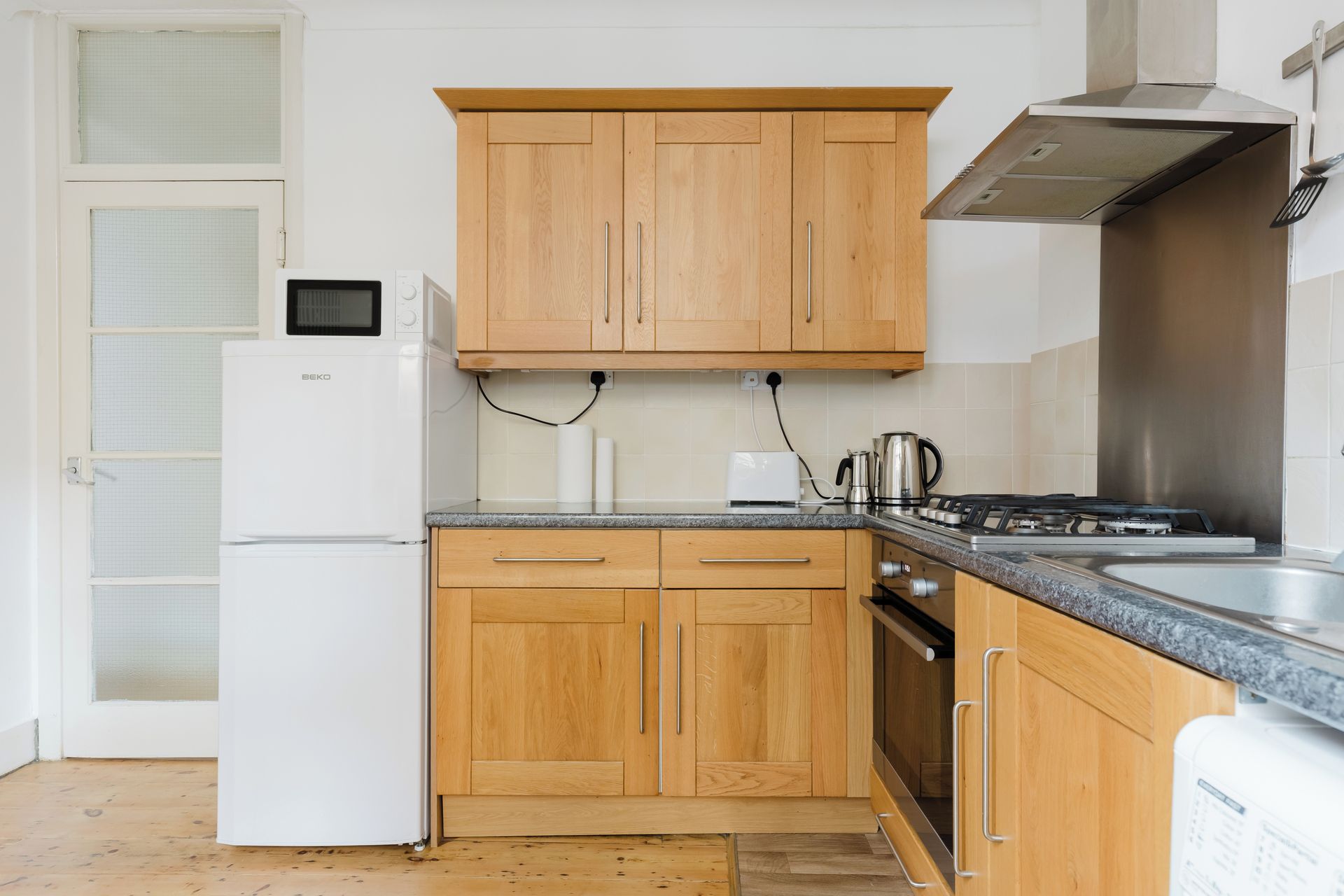 A kitchen with wooden cabinets, a built-in microwave, a gas stove, and a stainless steel range hood.