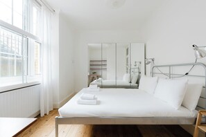 A modern hotel room with a large bed, bedside lamps, a bedside table, and a view through a window. - Timeless Retreat 5 Minutes from Tower Bridge (Greater London)