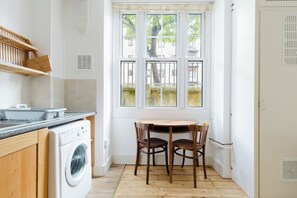 A compact kitchen with a washing machine, a sink, and a window with a view of the outside. - Timeless Retreat 5 Minutes from Tower Bridge (Greater London)