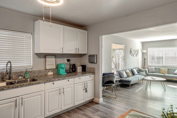 A modern kitchen with white cabinets, a granite countertop, and a coffee machine. - Bakersfield Home w/ Workspace, Near Hospitals (Bakersfield)