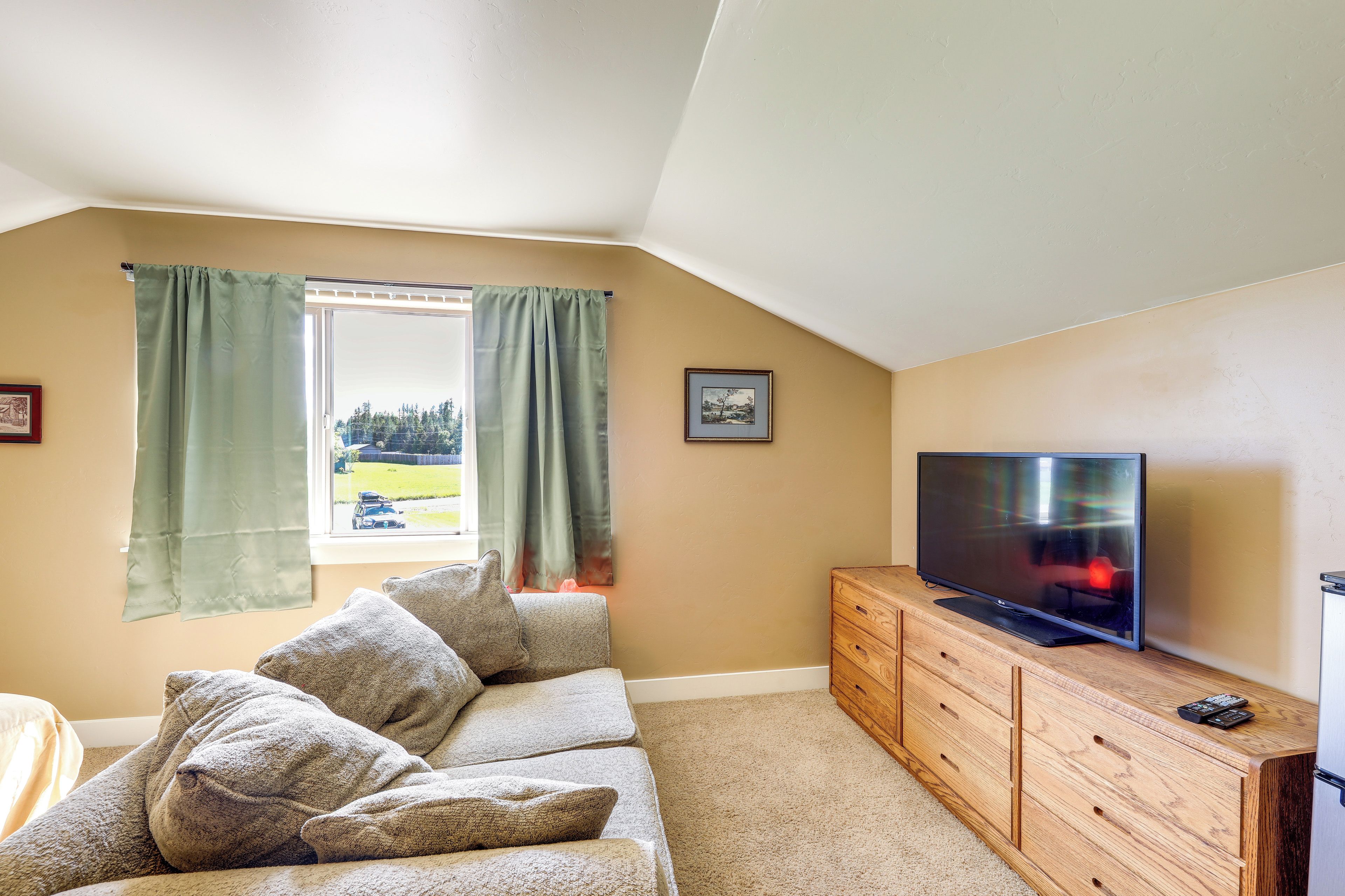 A cozy living room with a sofa, a flat-screen TV, and a wooden cabinet.