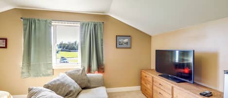 Una sala de estar acogedora con un sofá, un televisor de pantalla plana y un aparador de madera.