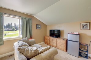 A cozy living room with a sofa, a television, a wooden cabinet, and a refrigerator. - Couple’s Retreat 4 Mi to Dtwn! Gateway to Glacier (Columbia Falls)