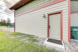 A building with a green siding exterior, a red-framed door, and a small porch area with a doormat. - Couple’s Retreat 4 Mi to Dtwn! Gateway to Glacier (Columbia Falls)