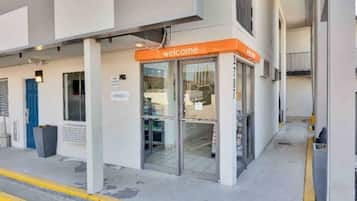 Entrada de un edificio con un letrero de 'Bienvenido', un cartel de oficina y una cámara de seguridad.