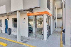 A building entrance with a 'Welcome' sign, an office sign, and a security camera.