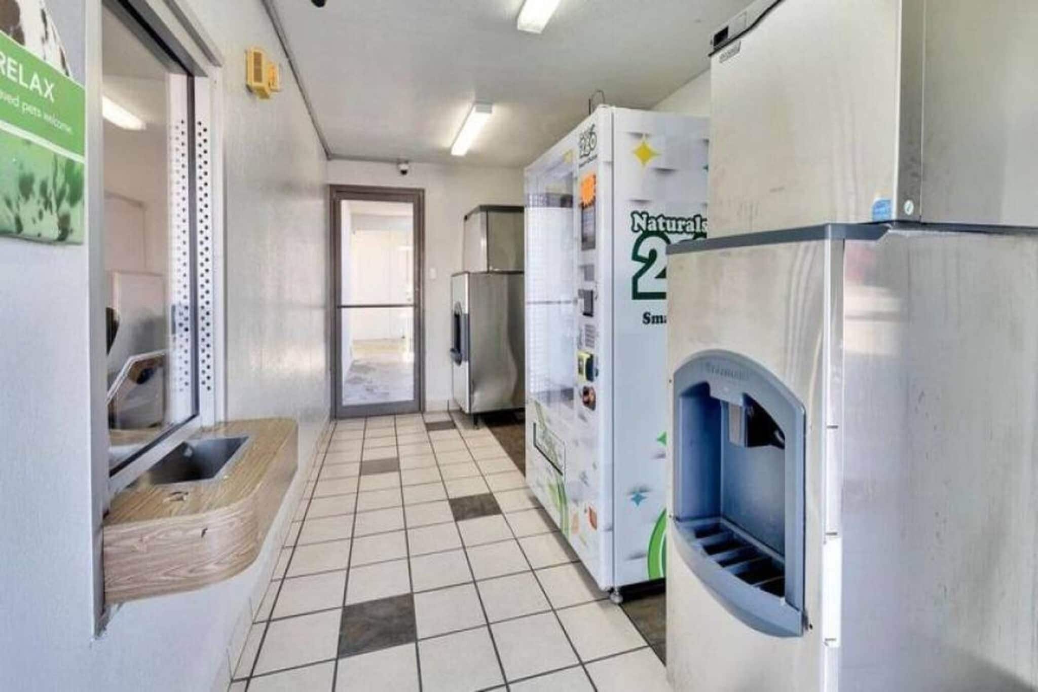 A hallway with a tiled floor, a sink, and a refrigerator.