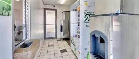 A hallway with a tiled floor, a sink, and a refrigerator.